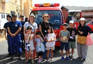 大人と子供が消防車の前で並んでいる写真